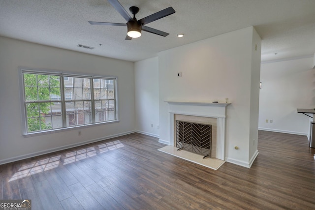 unfurnished living room featuring baseboards, visible vents, wood finished floors, ceiling fan, and a fireplace
