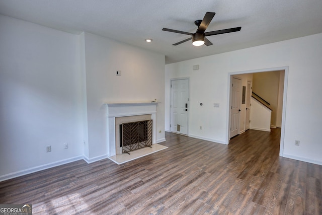 unfurnished living room with baseboards, a ceiling fan, wood finished floors, and a fireplace
