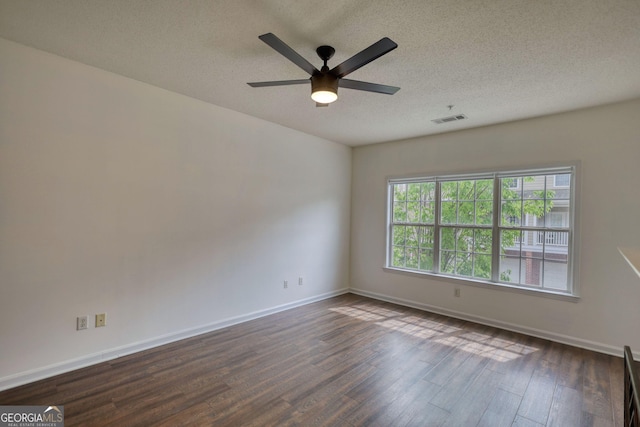 unfurnished room with a textured ceiling, ceiling fan, visible vents, baseboards, and dark wood-style floors