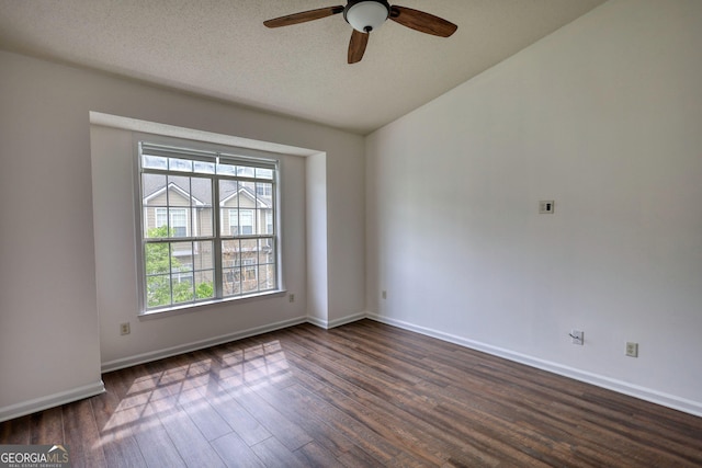empty room featuring dark wood finished floors, vaulted ceiling, a ceiling fan, and baseboards