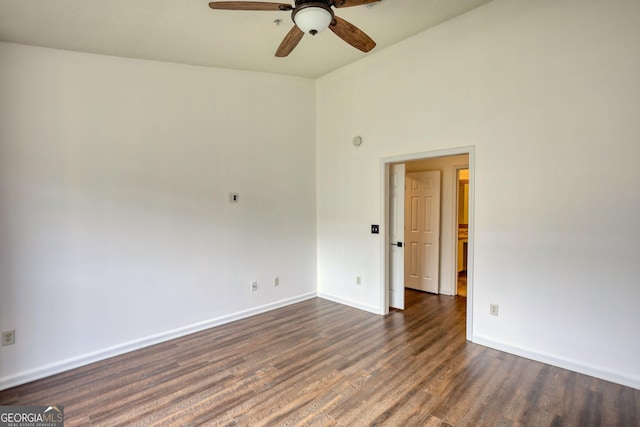 empty room featuring baseboards, a ceiling fan, and dark wood-style floors