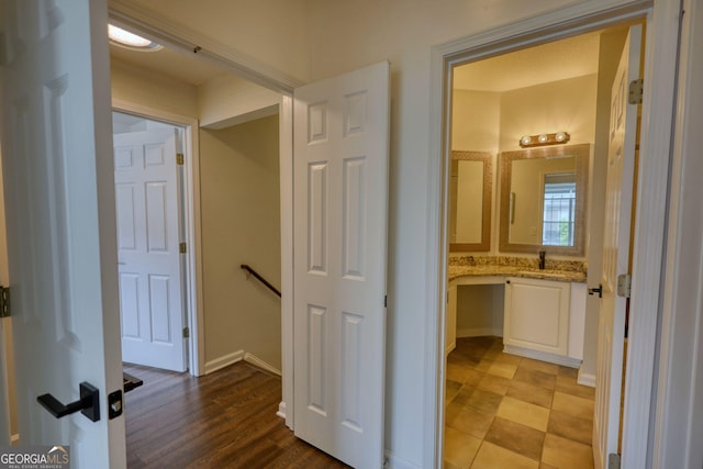 hallway featuring baseboards, an upstairs landing, and a sink