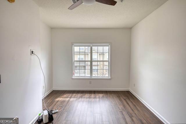 empty room with ceiling fan, baseboards, dark wood-type flooring, and a textured ceiling