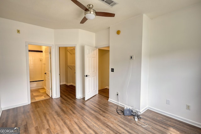 unfurnished bedroom with a spacious closet, wood finished floors, and visible vents