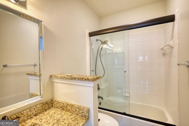 full bath with vanity, toilet, and bath / shower combo with glass door