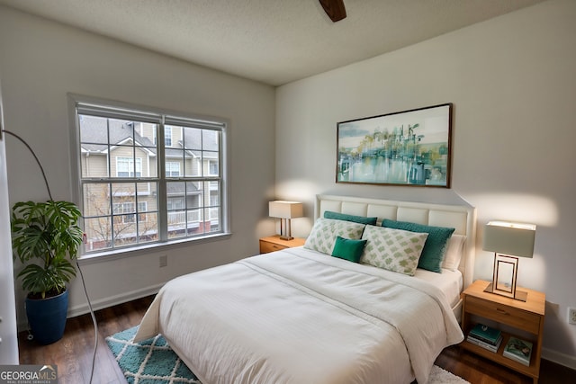 bedroom featuring baseboards, wood finished floors, and multiple windows