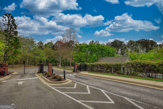 view of road featuring a gated entry, curbs, a gate, and sidewalks