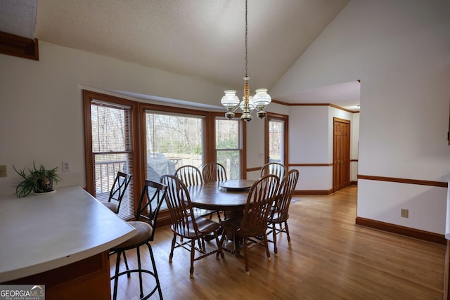 dining room featuring an inviting chandelier, light wood finished floors, vaulted ceiling, and baseboards