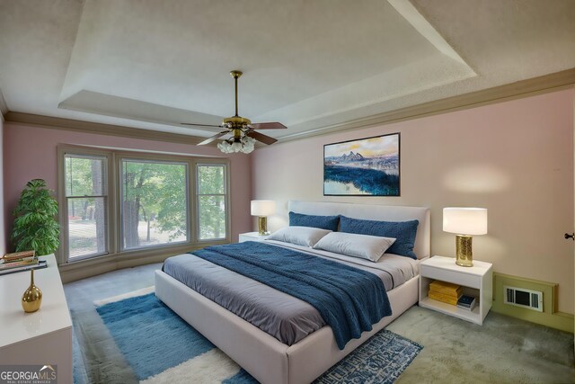carpeted bedroom with visible vents, ceiling fan, and a raised ceiling