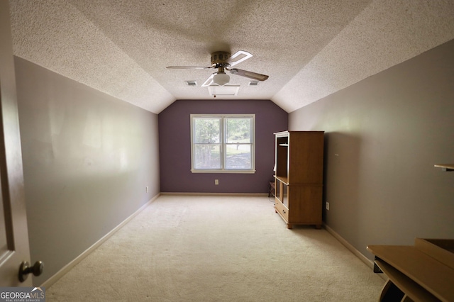 additional living space featuring a ceiling fan, vaulted ceiling, light colored carpet, and a textured ceiling
