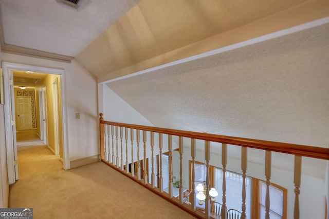 hall featuring baseboards, visible vents, lofted ceiling, and carpet