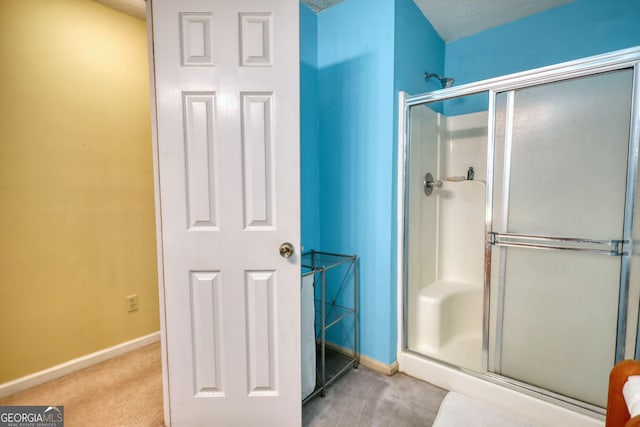 bathroom with baseboards, a stall shower, and a textured ceiling
