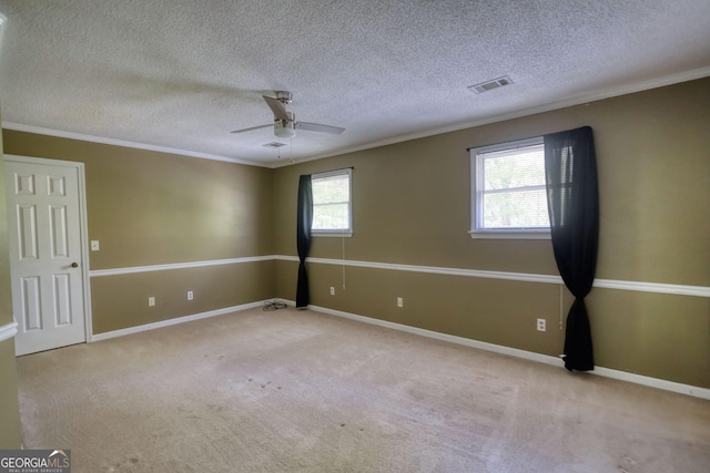 spare room with carpet, visible vents, ceiling fan, and crown molding