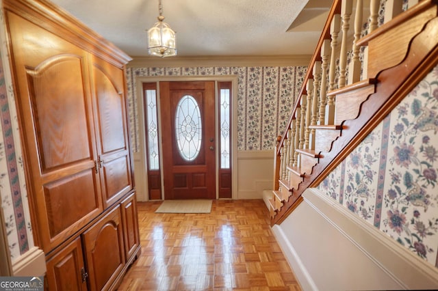 entrance foyer featuring crown molding, a wainscoted wall, stairway, and a decorative wall