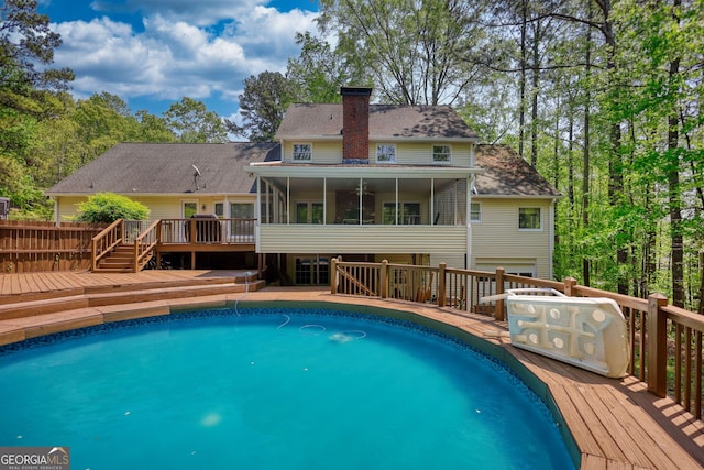 outdoor pool with a deck and a sunroom