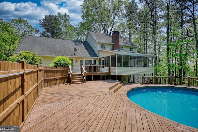 view of swimming pool featuring a fenced in pool, a wooden deck, and a sunroom