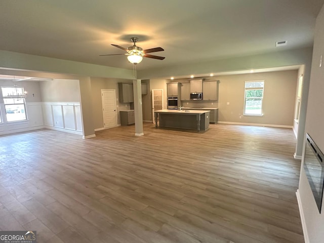 165 Jodi Pl, Locust Grove, GA 30248 - unfurnished living room featuring wainscoting, light wood-type flooring, ceiling fan, baseboards, and visible vents