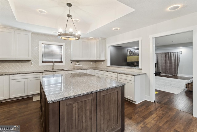 kitchen featuring a sink, decorative light fixtures, dark wood finished floors, backsplash, and a notable chandelier