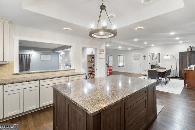 kitchen featuring a notable chandelier, dark wood-style floors, light stone counters, open floor plan, and white cabinetry