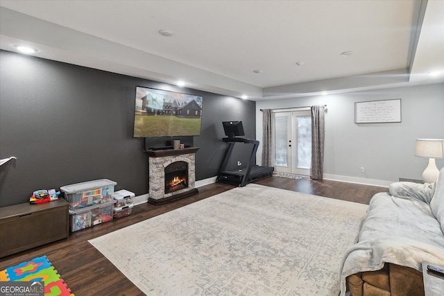 living room featuring a fireplace, baseboards, dark wood-style flooring, and french doors