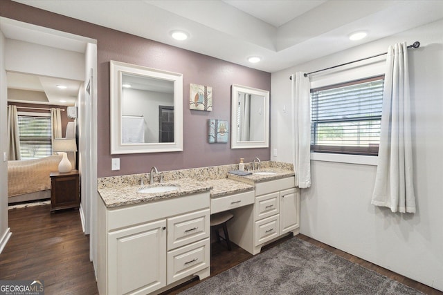 full bathroom with double vanity, wood finished floors, ensuite bathroom, and a sink