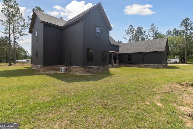 back of house featuring roof with shingles and a yard