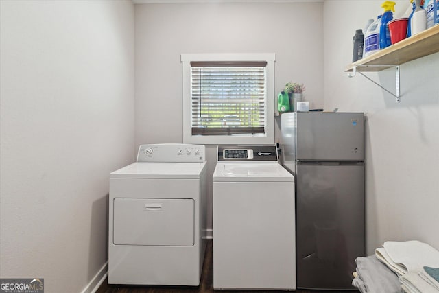 washroom with washing machine and clothes dryer, wood finished floors, and laundry area
