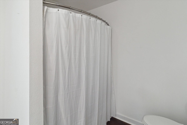 full bathroom featuring baseboards, curtained shower, and toilet