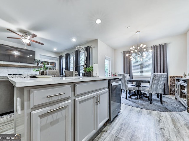 130 Maple Creek Way, Woodstock, GA 30188 - kitchen with stainless steel dishwasher, light countertops, ceiling fan with notable chandelier, and light wood-type flooring