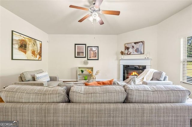 living area with a ceiling fan and a glass covered fireplace