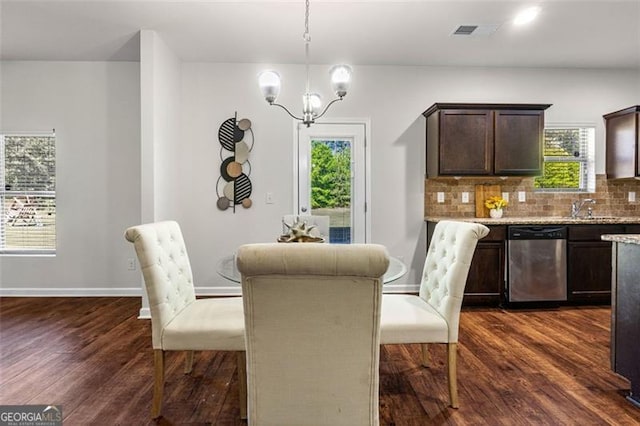 dining area with dark wood finished floors, visible vents, a wealth of natural light, and an inviting chandelier
