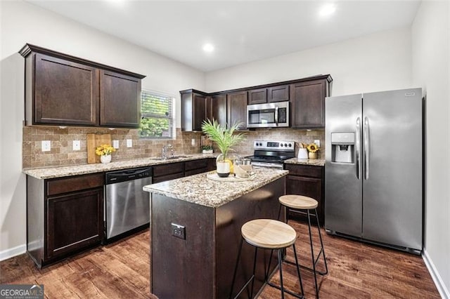 kitchen with stainless steel appliances, a center island, a sink, dark brown cabinets, and dark wood-type flooring