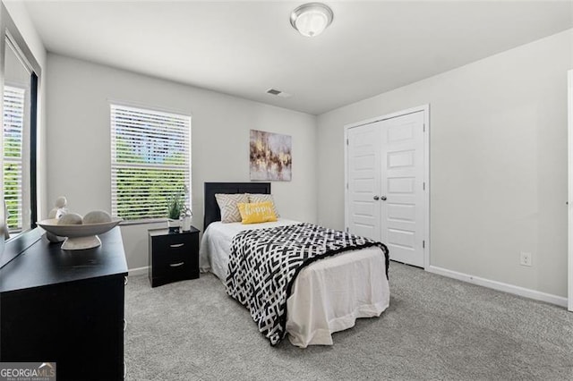 carpeted bedroom with a closet, visible vents, baseboards, and multiple windows