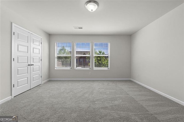 carpeted spare room featuring baseboards and visible vents