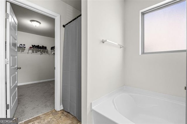 bathroom featuring a garden tub and a walk in closet