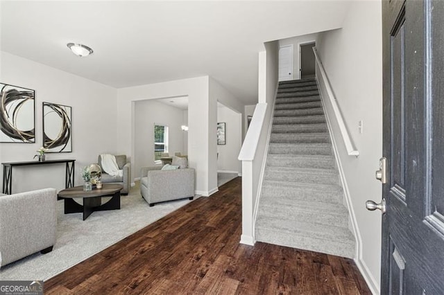 foyer with baseboards, wood finished floors, and stairs