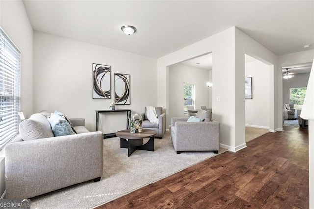 living room featuring baseboards, a ceiling fan, and dark wood-style floors