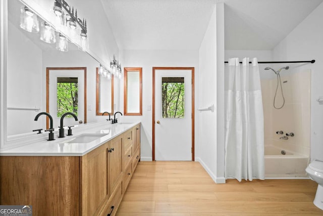 bathroom featuring double vanity, wood finished floors, shower / bath combination with curtain, and a sink