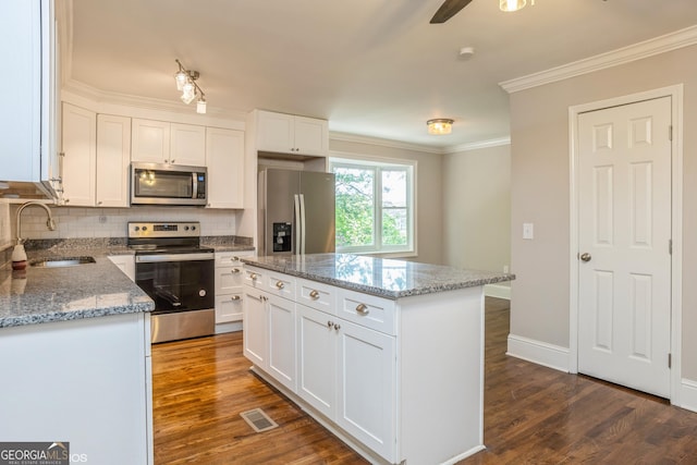 1531 E Broad St, Greensboro, GA 30642 - kitchen with backsplash, a sink, dark wood-type flooring, crown molding, and appliances with stainless steel finishes
