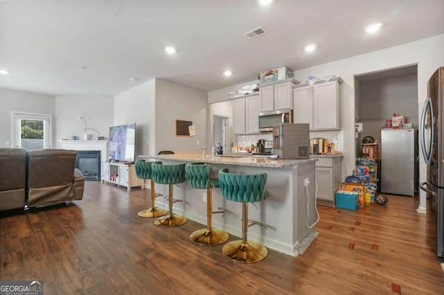 11893 Lovejoy Crossing Blvd, Hampton, GA 30228 - kitchen with appliances with stainless steel finishes, dark wood-style flooring, open floor plan, backsplash, and a kitchen breakfast bar
