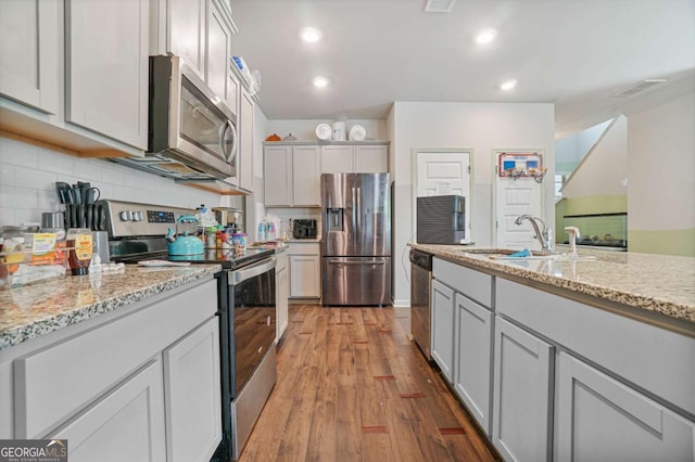 11893 Lovejoy Crossing Blvd, Hampton, GA 30228 - kitchen featuring stainless steel appliances, light wood-type flooring, tasteful backsplash, light stone counters, and recessed lighting