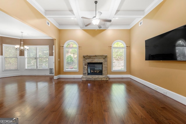 unfurnished living room featuring beam ceiling, coffered ceiling, ceiling fan with notable chandelier, a stone fireplace, and dark wood-type flooring