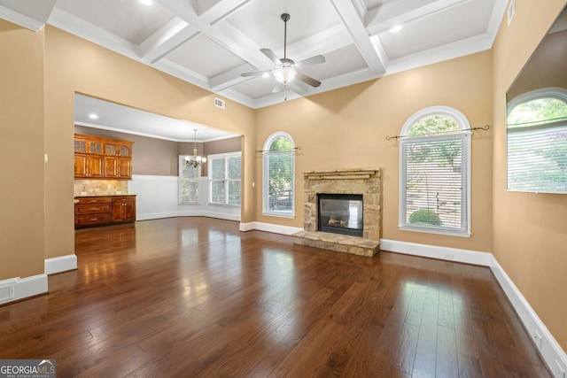 unfurnished living room featuring beam ceiling, dark wood-style flooring, and ceiling fan with notable chandelier