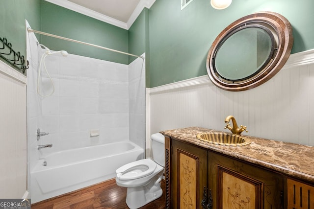 full bath featuring wood finished floors, bathtub / shower combination, a wainscoted wall, toilet, and ornamental molding