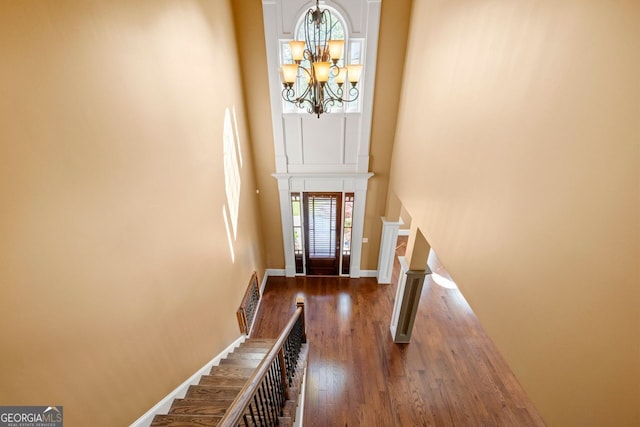 foyer with baseboards, an inviting chandelier, a high ceiling, wood finished floors, and stairway