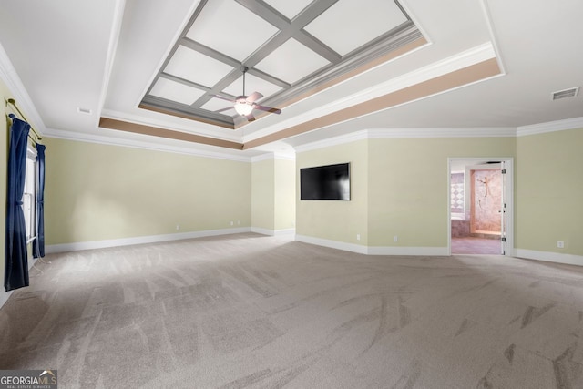 empty room with crown molding, ceiling fan, a tray ceiling, carpet flooring, and visible vents