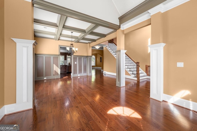 unfurnished living room featuring decorative columns, a chandelier, beamed ceiling, stairway, and hardwood / wood-style flooring