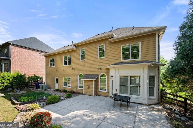 back of property with fence, roof with shingles, central AC, and a patio