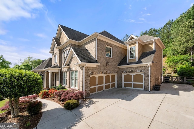 view of front of home with driveway, brick siding, roof with shingles, and a garage