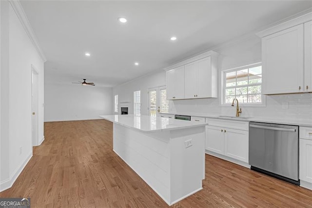 kitchen featuring ceiling fan, backsplash, dishwasher, a sink, and ornamental molding